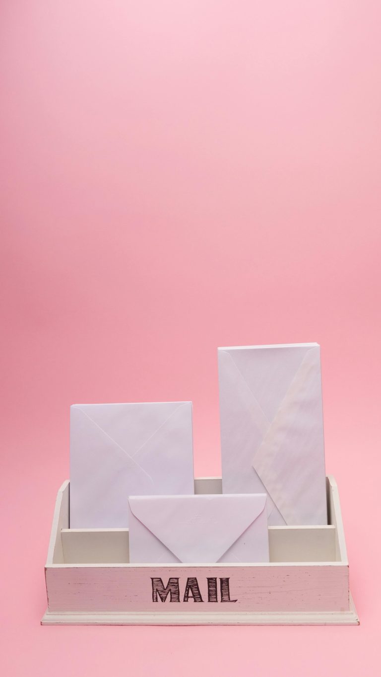 Simple and elegant minimalist mailbox with envelopes on pink background.